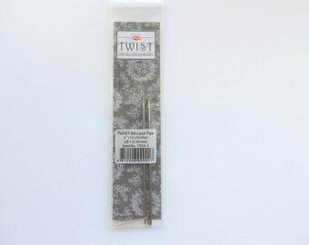 May include: A package of two silver Twist SS Lace Tips knitting needles, size 4 (110 cm/4 inch) or US 1 (2.25 mm). The package has a gray background with a white floral pattern and the text "Twist SS Lace Tips 4"/110 cm/Mini US 1 (2.25 mm) Item No. 7504-1" printed on a white label.