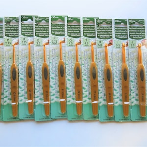 May include: A set of ten gold crochet hooks in individual packaging. The hooks are labeled with their size in millimeters, ranging from 2.25 mm to 6.0 mm. The packaging is green and white with the Clover brand name.