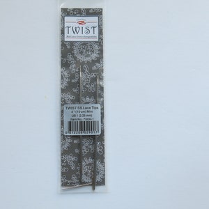 Peut inclure: Un paquet de deux aiguilles &agrave; tricoter en argent Twist SS Lace Tips, taille US 1 (2,25 mm), de 4 pouces (10 cm) de long. L'emballage a un fond blanc avec un motif floral gris et le texte "TWIST SS Lace Tips 4 (10 cm) Mini US 1 (2,25 mm) Item No. 7504-1" imprim&eacute; dessus.
