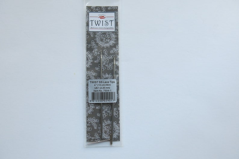 Peut inclure: Un paquet de deux aiguilles &agrave; tricoter en argent Twist SS Lace Tips, taille US 1 (2,25 mm), de 4 pouces (10 cm) de long. L'emballage a un fond blanc avec un motif floral gris et le texte "TWIST SS Lace Tips 4 (10 cm) Mini US 1 (2,25 mm) Item No. 7504-1" imprim&eacute; dessus.