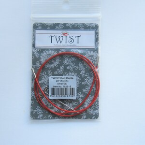 Puede incluir: Cable de tejer rojo con dos agujas de metal, empaquetado en una tarjeta gris con letras blancas. La tarjeta dice "TWIST Red Cable 22" (55 cm) Small [5] Item No. 7522-8".