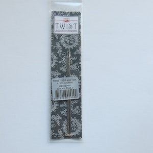 Peut inclure: Une aiguille Twist 95 Lace Tips argent&eacute;e dans un emballage en plastique sur fond gris. L'emballage porte l'inscription "Twist 95 Lace Tips 4" (10 cm) Mini US 0 (2 mm) Item No. 7594-0".