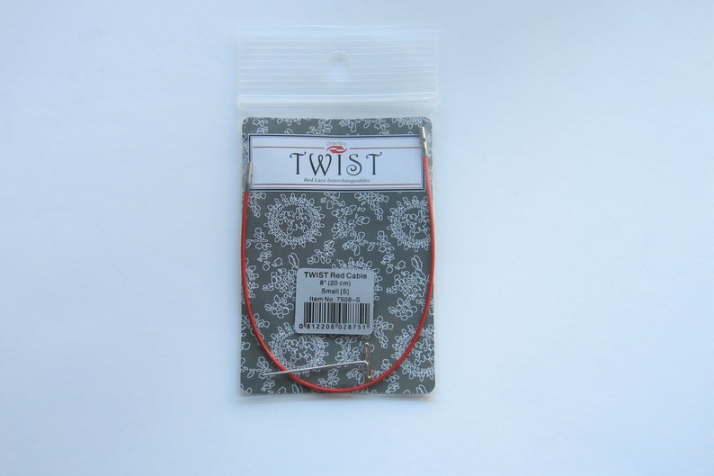 Puede incluir: Aguja de tejer de cable roja en un paquete de pl&aacute;stico. El paquete es gris con dise&ntilde;os florales blancos y el texto "TWIST Red Cable 8" (120 cm) Talla (8) N.&ordm; de art&iacute;culo 7506-8".