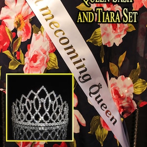 May include: White satin sash with gold lettering that reads "Homecoming Queen" and a silver tiara with rhinestones. The sash and tiara are on a black fabric with a floral pattern.