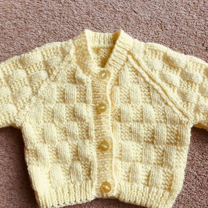 Pu&ograve; includere: Un cardigan per neonati lavorato a mano, di colore giallo chiaro, con un motivo a trama a cestino. Il maglione ha uno scollo a V, maniche lunghe ed &egrave; chiuso con quattro bottoni rotondi giallo chiaro. L'indumento &egrave; realizzato in filato morbido.
