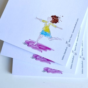 Könnte beinhalten: Ein Stapel weißer Grußkarten mit einer Aquarellillustration einer Person mit braunen lockigen Haaren, die ein gelbes Oberteil und einen blauen Rock trägt und über eine violette Pfütze rennt. Der Text Edition Zebrafisch Karin Tauer www.zebrafisch.com ist aufgedruckt.