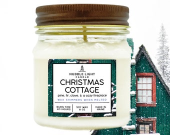 May include: A jar candle with a brown lid and a label that reads "Christmas Cottage." The label includes the text "pine, fir, clove, & a cozy fireplace." The candle is 8 oz and has a 40-hour burn time.