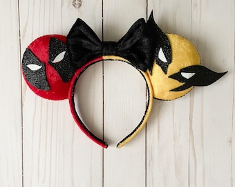 May include: A pair of novelty ears featuring a red and black design on one ear and a yellow and black design on the other. A black bow sits atop the headband. The headband is red and yellow.