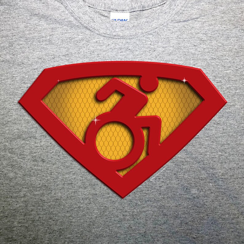 K&ouml;nnte beinhalten: Ein graues T-Shirt mit einem roten Superman-Logo. Das Logo hat einen gelben Hintergrund mit einem Schuppenmuster. Im Inneren des Logos befindet sich ein Rollstuhlsymbol.