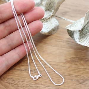 Op de afbeelding: Een zilveren slangenketting met een karabijn sluiting.