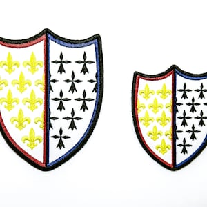 Peut inclure: Deux patchs brodés en forme de bouclier. Le plus grand patch est rouge, blanc et bleu avec des fleurs de lys dorées sur le côté gauche et des taches d'hermine noires sur le côté droit. Le plus petit patch est du même design mais plus petit.