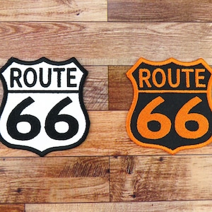 Peut inclure: Deux patchs brodés Route 66. Un patch est blanc avec des lettres et des chiffres noirs. L'autre patch est noir avec des lettres et des chiffres orange.