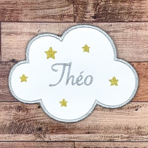 Può includere: Toppa a forma di nuvola bianca con contorno argentato e stelle ricamate in oro. Il nome "Théo" è ricamato in argento sulla toppa.