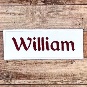 May include: White rectangular patch with a red embroidered name "William" on it.