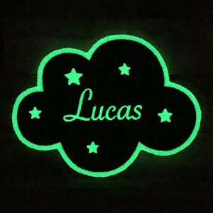以下が含まれることがあります： 緑色の暗闇で光る輪郭を持つ黒い雲の形をしたパッチ。パッチには白い星が5つと、白い筆記体で「Lucas」という名前が書かれている。