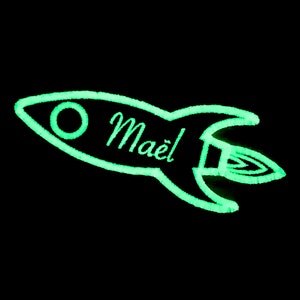 May include: A green glow-in-the-dark rocket ship with the name "Maël" written on it.