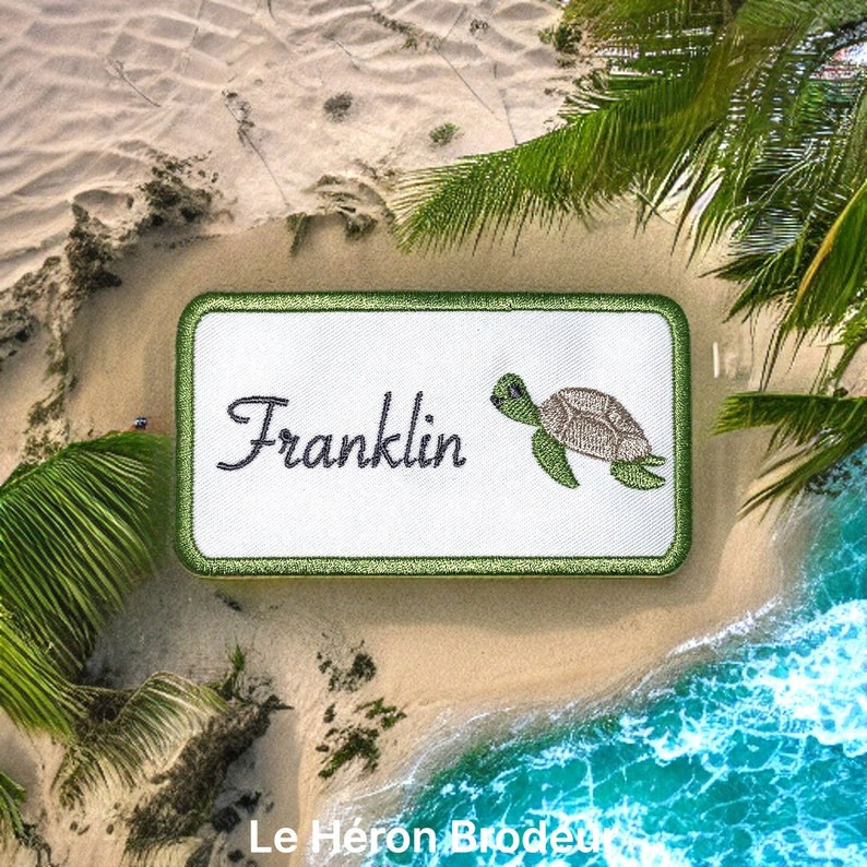 May include: A white embroidered patch with a green border. The patch features the name "Franklin" in cursive script and a green sea turtle with a brown shell.