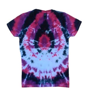 May include: A V-neck t-shirt with a tie-dye pattern in shades of pink, purple, black, and white. The short-sleeved shirt has a symmetrical design, with the colors radiating from the center.