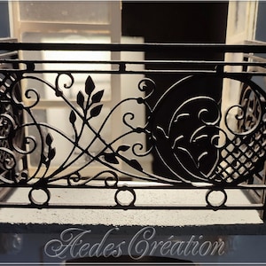 Puede incluir: Barandilla de balcón de metal negro con un diseño decorativo que presenta hojas y espirales estilizados. La barandilla está montada en una repisa de hormigón.