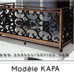 Puede incluir: Un modelo de madera de una barandilla de balcón con un diseño decorativo e intrincado. La barandilla está hecha de madera marrón y tiene un diseño de metal negro. El modelo está etiquetado como "Modèle KAPA".