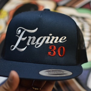 May include: A navy blue trucker hat with a white embroidered cursive "Engine" and a red embroidered "30".