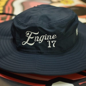 May include: A navy blue bucket hat with a white embroidered logo that says "Engine 17".