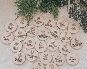 May include: A set of 25 wooden Christmas countdown ornaments with various festive activities and phrases, such as "Bake some cookies", "Go on a Christmas scavenger hunt", "Watch a Christmas movie", and "Surprise someone with a gift".