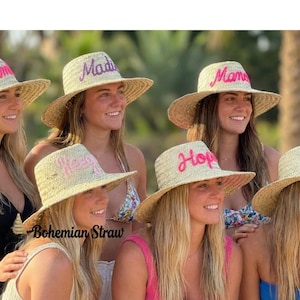 Könnte beinhalten: Eine Gruppe von Frauen trägt Strohhüte mit gestickten Namen in verschiedenen Farben. Die Hüte haben breite Krempen und sind mit Namen wie "Cam", "Madi", "Mom", "Hope" und "Eve" versehen. Die Hüte sind von "Bohemian Straw".