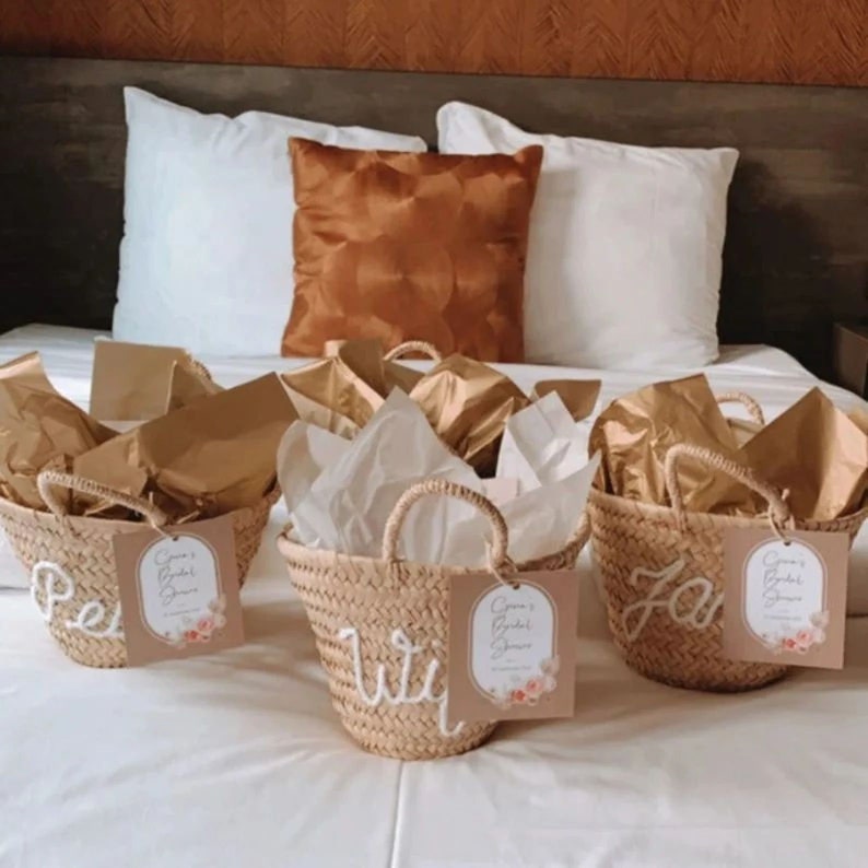 K&ouml;nnte beinhalten: Vier kleine geflochtene K&ouml;rbe mit wei&szlig;en Griffen und personalisierten Namen, "Peri", "Wil", "Za" und "Bri", mit einem Etikett mit der Aufschrift "Groom's Bridal Shower".