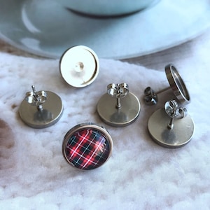 May include: Four silver earring settings, three with backs and one with a red and white tartan design.