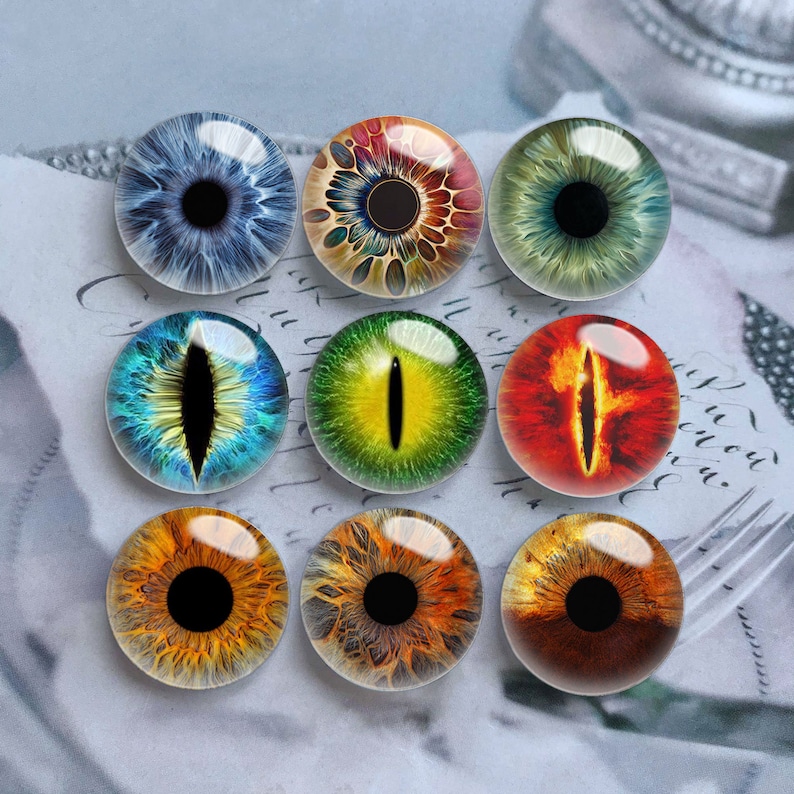 May include: Nine round glass cabochons with different eye designs. The eyes are in various colors, including blue, green, yellow, orange, and red. The eyes have different pupils, including round, slit, and cat-eye shapes.