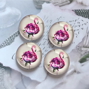 May include: Four clear, round glass cabochons with a flamingo and peony design. The flamingo is pink with a curved neck, and the peony is a vibrant magenta. The cabochons are set against a soft, neutral background.