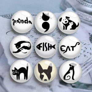 May include: Nine white, round glass magnets with black illustrations of animals and words. Designs include a panda, cat, dog, fish, and the word "cat". The magnets are arranged in a grid pattern.