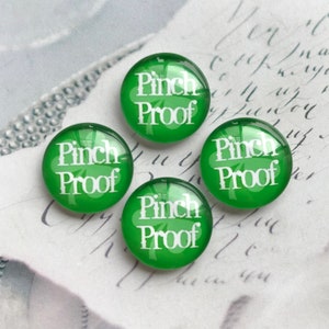 May include: Four green glass cabochons with white shamrock designs and the text "Pinch Proof" on each.