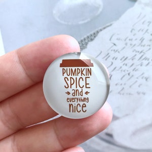May include: A white round glass cabochon with a brown coffee cup graphic and the text "Pumpkin Spice and everything nice".