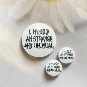 May include: Three white button badges with black text that reads "1. MYSELF AM STRANGE AND UNUSUAL".