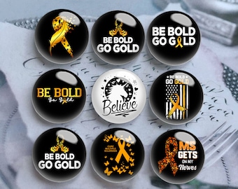 May include: A collection of nine round, glossy black and white buttons. The buttons feature various designs, including gold ribbons, the text "BE BOLD GO GOLD", a unicorn, and the text "Believe". Some buttons also have the text "Cure Multiple Sclerosis" and "MS Gets on my Nerves".