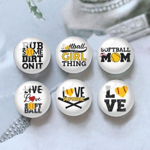 May include: Six white round buttons with black and yellow softball-themed designs. The designs include "Rub Some Dirt On It", "Softball It's A Girl Thing", "Softball Mom", "Live Love Softball", "Love Softball", and "Love".