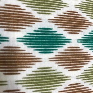 May include: Close-up of a white fabric featuring a repeating diamond pattern. The diamonds are formed by horizontal lines in brown, green, and teal hues. The pattern is evenly spaced, creating a textured effect across the fabric.