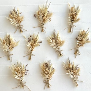 May include: Ten small bouquets of dried flowers in shades of cream and beige, tied with twine. The bouquets are arranged in two rows of five on a white surface.