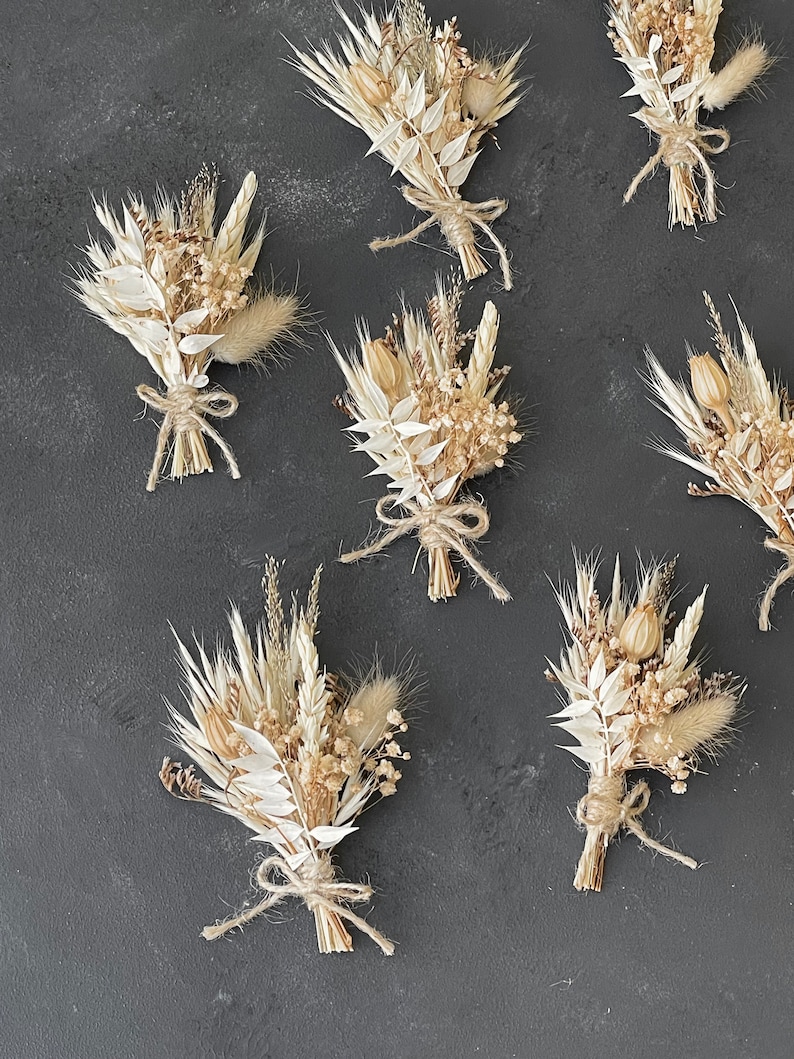 May include: Six small bouquets of dried flowers in shades of cream and beige. The bouquets are tied with twine and feature various dried grasses and flowers.