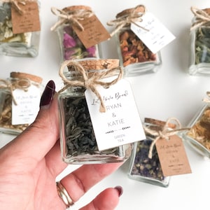 May include: Small glass jars filled with different types of tea, tied with twine and a tag that says "Let's Love Brew Ryan & Katie Green Tea".