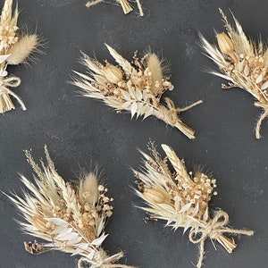 May include: A set of six dried flower bouquets tied with twine. Each bouquet features a variety of dried grasses, flowers, and seed pods in shades of beige and cream.