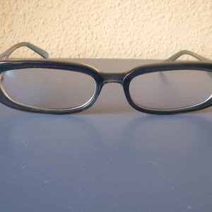 Könnte beinhalten: Eine Brille mit schwarzen, ovalen Gläsern und klaren Linsen.