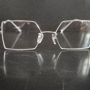 Könnte beinhalten: Silberfarbene quadratische Brille mit klaren Gläsern.