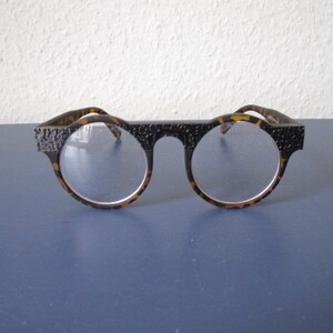 Puede incluir: Gafas redondas de carey con montura texturizada.
