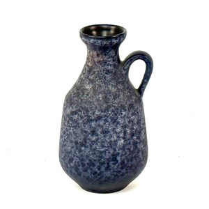 Könnte beinhalten: Eine blau-graue Keramikvase mit Henkel. Die Vase hat eine strukturierte Oberfläche und einen dunklen Innenraum. Die Vase ist etwa 20 cm hoch.