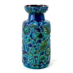 Op de afbeelding: Een blauwe en groene keramische vaas met een bloemenmotief. De vaas heeft een brede opening en een smalle hals.