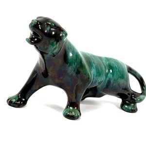Könnte beinhalten: Keramik-Panther-Figur in Grün- und Schwarztönen. Die Skulptur hat eine glänzende Oberfläche und ist in einer dynamischen, brüllenden Pose dargestellt. Die Figur ist ein dekorativer Artikel, der sich für die Inneneinrichtung eignet.