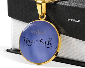 May include: A gold necklace with a round pendant featuring a blue background and the words "Have Faith" in black cursive script. A gold floral design is above the text.